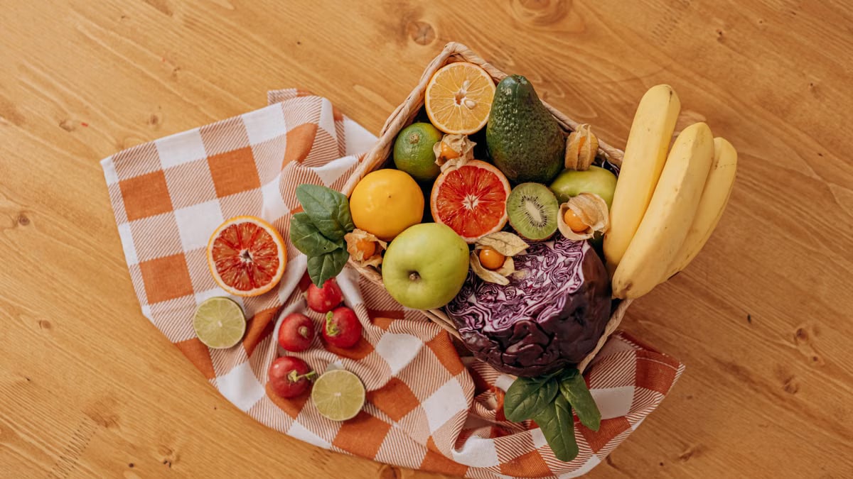 A vibrant flat lay of assorted fresh fruits on a checkered cloth over a wooden surface, perfect for healthy lifestyle concepts.
